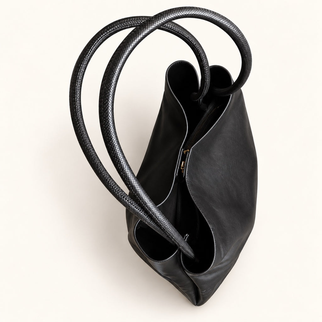 Top view of the black tote bag, showing the open main compartment, folded side construction and long, textured handles.